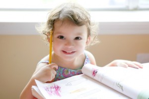 Little toddler girl writing at school desk